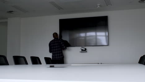 A-static-shot-of-a-man-trying-to-turn-on-the-monitor-in-a-conference-room