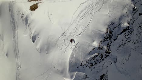 bottom-up-drone-shot-of-a-snowboarder-on-a-snowy-mountain-top-in-Switzerland