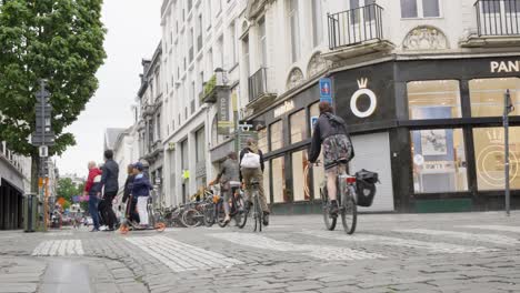 Simplemente-Coma-Un-Repartidor-De-Comida-Para-Llevar-Vestido-Con-Traje-Naranja-En-Bicicleta-En-El-Concurrido-Centro-Urbano-De-Gante,-Bélgica