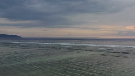 aerial-of-small-waves-ripple-continuously-during-low-tide-through-the-ocean-at-sunset