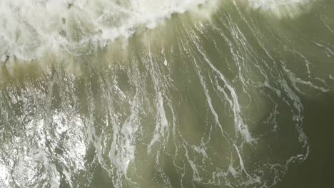 Waves-break-dramatically-over-the-shoreline-of-beach-Topdown-aerial