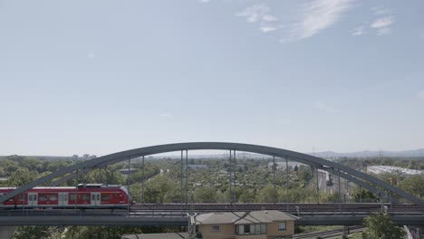 Red-train-crossing-reinforced-steel-bridge-in-Frankfurt,-Germany