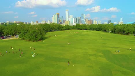 People-playing-sports-in-Zikler-Park-in-Austin,-Texas-with-the-city-skyscrapers-in-the-background