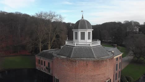 Aerial-pan-around-the-lighthouse-top-of-the-tower-of-moated-Rosendael-castle-with-winter-garden-and-pond-in-the-background