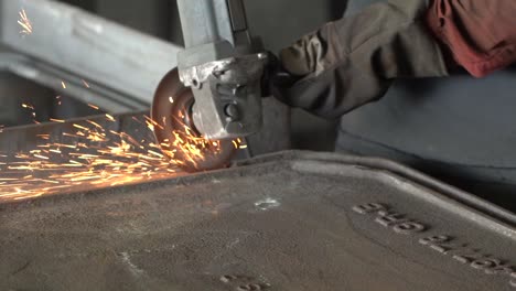 Industrial-metal-grinding-process-in-metal-casting-factory-with-circular-saw-tool,-closeup-slow-motion-shot-of-sparks-flying-from-hot-metal