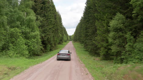 REVEAL-AERIAL---A-2020-Tesla-Model-3-driving-down-a-forested-dirt-road