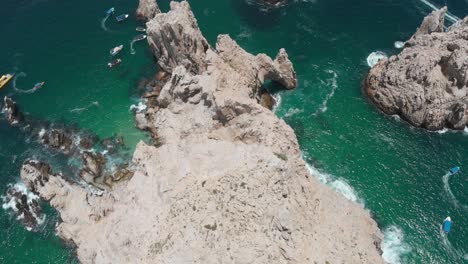 Aerial-View-of-Rock-Formations-in-Ocean-with-Boats-and-Coastal-Town