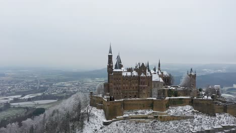Aerial-view-rotating-around-stunning-medieval-Castle-Hohenzollern-on-a-snowy-day-during-winter-in-Swabia,-Germany