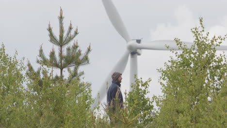 WIDE-SHOT,-A-handsome-man-stops-to-look-at-a-wind-turbine-during-his-countryside-walk