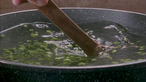 Cooking-peas-in-a-pot,-shaking-the-water-with-a-wooden-spatula