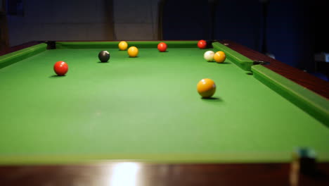 A-man-potting-a-yellow-ball-on-a-pool-table-in-to-the-center-pocket