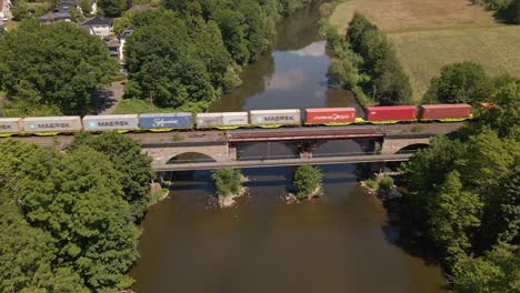 Long-colourful-freight-train-crossing-a-river-bridge-on-a-sunny-day-in-Germany