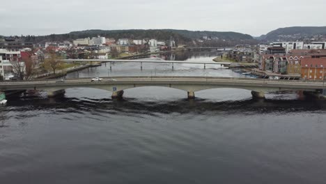 Kristiansand-city-bridges-crossing-river-Otra---Forward-moving-aerial-above-river-during-cloudy-morning---Norway