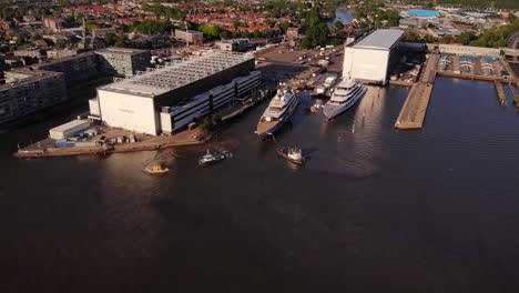 Aerial-View-Of-Tug-Boats-Assisting-Luxury-Yacht-To-Dock-At-Oceanco-Shipyard-Marina-Located-In-Alblasserdam