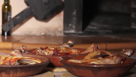 Suckling-lamb-quarters-recently-baked-in-an-ancient-clay-wood-oven,-at-the-background-of-the-image