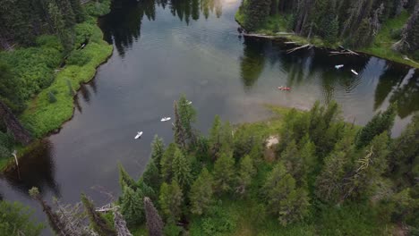 Counterclockwise-drone-shot-of-paddleboarders-and-kayakers-coming-around-a-bend-in-the-Payette-River-in-the-Idaho-wilderness
