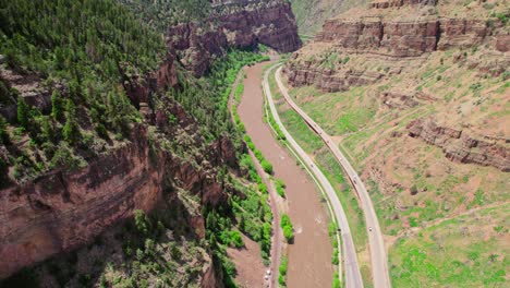 Toma-Aérea-De-Drones-Del-Río-Colorado-Que-Fluye-A-Través-Del-Profundo-Desfiladero-Del-Cañón-Junto-A-La-Autopista-Interestatal-I-70-En-Glenwood-Canyon-Colorado,-EE.UU.