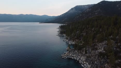 Drone-shot-of-the-rocky-East-shore-of-Lake-Tahoe-and-the-surrounding-forest-at-sunset