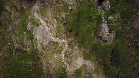 Drone-shot-of-a-natural-path-in-the-swiss-alps,-people-are-walking