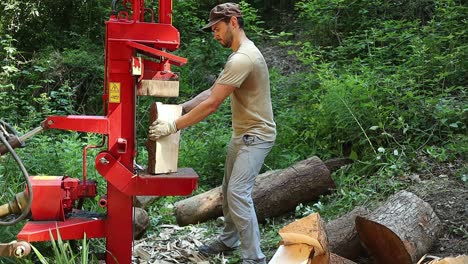 A-man-surrounded-by-small-logs-that-he-is-cutting-up-with-a-hydraulic-wood-splitter