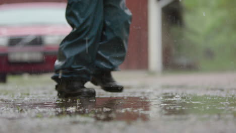 SLOW-MOTION,-A-child-in-wet-weather-gear-walks-through-the-heavy-rain