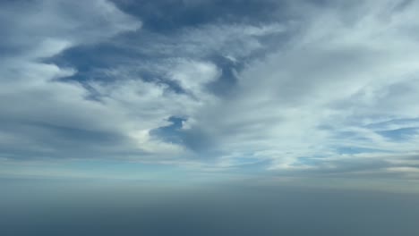 Vista-De-La-Cabina-Desde-Un-Avión-Que-Volaba-Debajo-De-Unas-Pocas-Nubes-Blancas-Con-Un-Cielo-Azul-Profundo,-Luz-Del-Día
