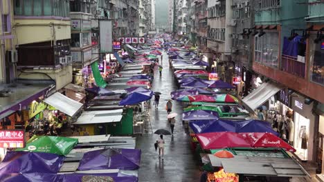 Ladies-Retail-Market,-People-Walk-Under-Umbrellas-on-Rainy-Day,-Mong-Kok,-Hong-Kong