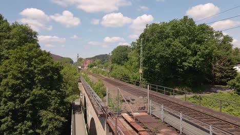 Freight-train-heading-off-into-the-distance-viewed-from-a-rusty-old-train-trestle