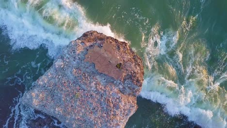 Aerial-birdseye-view-of-abandoned-seaside-fortification-buildings-at-Karosta-Northern-Forts-on-the-beach-of-Baltic-sea-,-waves-splash,-golden-hour-sunset,-low-wide-drone-shot
