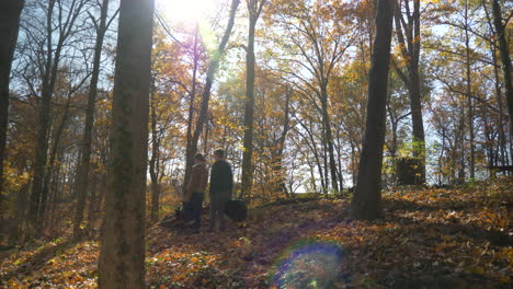 wide-shot-of-two-musicians-walking-in-the-woods-in-the-fall