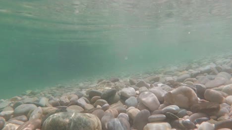 Underwater-shot-Crystal-clear-sea-with-pebbles-bottom,-tracking-motion