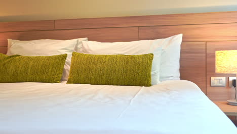 Pan-left-to-right-across-a-bed-decorated-with-green-throw-pillows