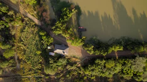 Aerial-top-down-view-of-isolated-independent-rural-house-with-solar-panel-close-to-a-lake-at-sunset