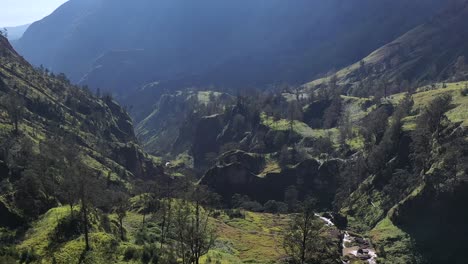 Warm-spring-water-stream-along-a-narrow-canyon-in-Mount-Rinjani-Volcano-crater-in-Indonesia,-Nusa-Tenggara,-Aerial-flyover-shot