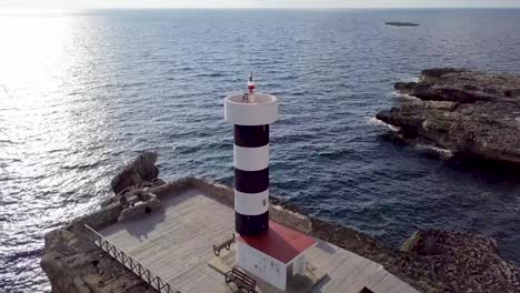 Drone-Footage-Of-Lighthouse-In-Sant-Jordi,-Mallorca,-Spain-With-Blue-Waves