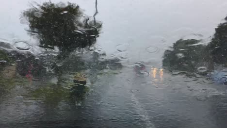 Heavy-rain-falls-on-car-windscreen-as-other-vehicles-pass