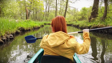 Outdoor-Woman-with-Yellow-Coat-in-Kayak-on-a-River-in-Stunning-Nature