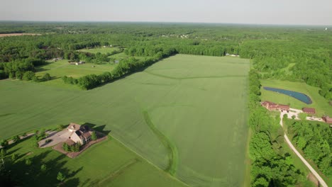 Aerial-view-of-farm-house-among-green-fields-and-slopes-in-rural-countryside