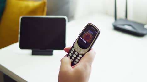 man-holding-old-mobile-NOKIA-3310-try-to-use-and-touch-button-and-check-signal-to-connect-in-the-year-2022