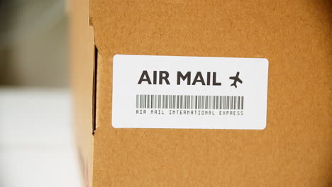 Hände-Bringen-Luftpost-Aufkleber-Auf-Einem-Karton-Mit-Internationalem-Express-Barcode-An