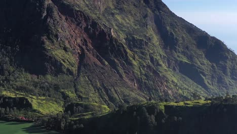 Mount-Rinjani-Volcano-walls-and-campsite-near-the-lakeshore-in-Nusa-Tenggara-Indonesia,-Aerial-approach-shot
