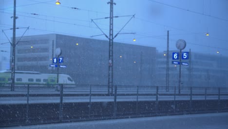 Heavy-winter-snowfall-at-multi-track-train-station,-grey-overcast-day