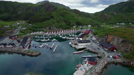 Aerial-backwards-shot-of-a-Norwegian-marina-harbor-in-Helgeland,-Tonnes,-clouds-reflecting-on-the-surface