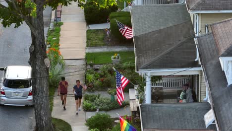 Two-people-walking-down-a-sidewalk-in-small-town-suburban-America