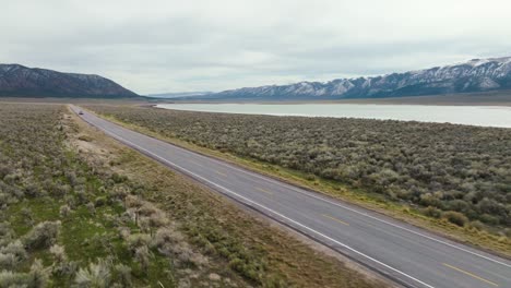 AERIAL---Truck-on-highway-next-to-Scipio-Lake,-Utah,-wide-panoramic-reverse-shot