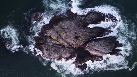 A-birds-eye-drone-video-looking-down-towards-some-large-rocks-above-the-ocean