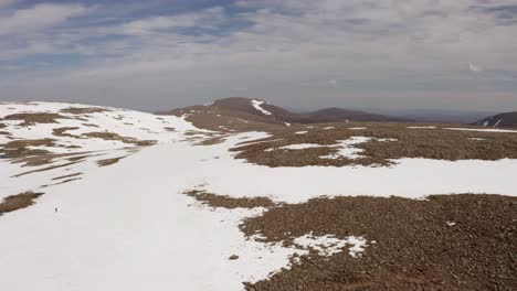 Schottlands-Bergplateau-Mit-Schnee-Bedeckt,-Drohne-Mit-Laufender-Person
