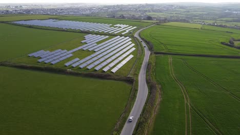 Distant-shot-looking-down-on-solar-farm-panels-green-fields-background