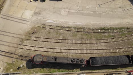 Diesel-locomotive-hauling-carts-full-of-coal,-aerial-top-down-view