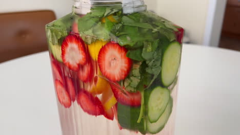 Close-Up-of-Glass-Carafe-Filled-with-Fruit-Infused-Spa-Water,-Lemon-Strawberry-and-Basil